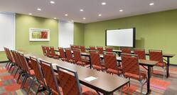 Classroom Setup in Conference Room With Tables and Chairs Facing Presentation Screen on Green Wall, Windows, and Wall Art