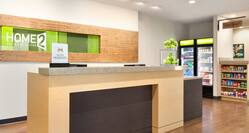 Hotel Signage Behind Front Desk With Green Apples on the Counter and View of the Snack Shop