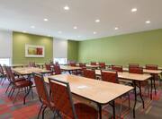 Classroom Setup in Conference Room With Tables and Chairs Facing Green Wall, Windows, and Wall Art