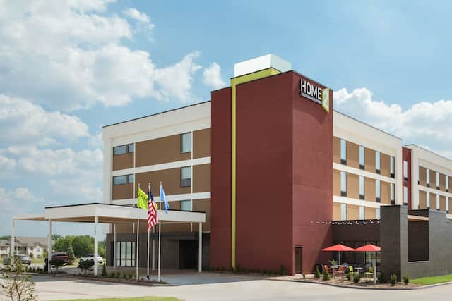 Daytime View of Signage on Hotel Exterior, Flagpoles, Driveway, and Landscaping