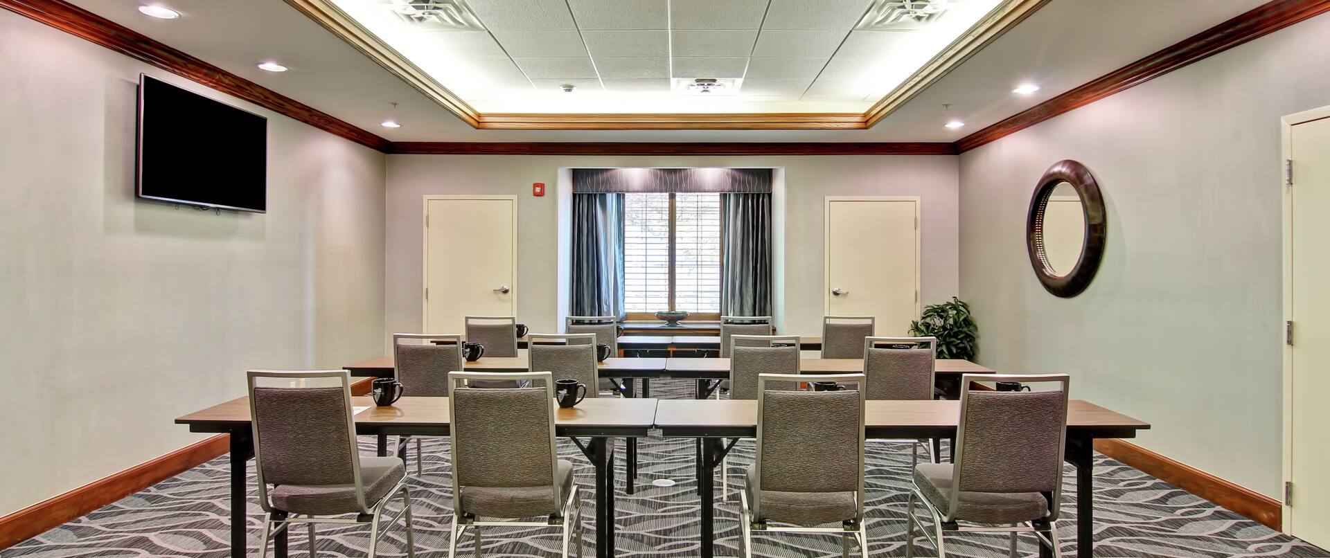 Classroom Setup in Meeting Room With TV, Tables and Chairs Facing Window With Open Drapes