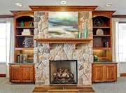 Fireplace With Wall Art Between Bookshelves and Windows With Long Drapes in the Lobby