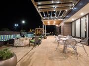 Illuminated Exterior Patio With Table Seating Under Pavilion, and Soft Seating by Fire Pit at Night