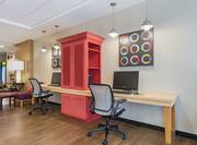 Brightly Lit Business Center with Colorful Wall Art, Red Storage Cabinet Between Two Computer Workstations with Ergonomic Chairs