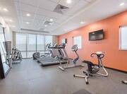 Fitness Center With Large Window, Cardio Equipment Facing TVs, and Water Cooler by Large Mirror