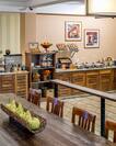 Long Wooden Table With Chairs, Wall Art, Wall Clock, Food Service Area With Plates, Utensils, Hot and Cold Breakfast Items