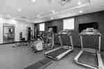 Fitness Center With Cardio Equipment Facing TVs, Large Mirror, Weight Bench, and Weight Balls