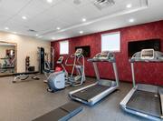 Fitness Center With Cardio Equipment Facing TVs, Large Mirror, Weight Bench, and Weight Balls