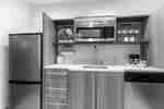 Kitchen With Fridge, Plates and Cups in Overhead Cabinets, Microwave Over Sink, Coffee Maker, and Dishwasher