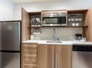 Kitchen With Fridge, Plates and Cups in Overhead Cabinets, Microwave Over Sink, Coffee Maker, and Dishwasher