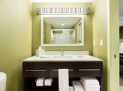 Toilet, Brightly Lit Vanity Mirror, Sink, Fresh Towels, and Toiletries in Guest Room Bathroom