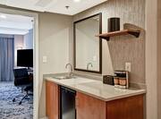 Wetbar in room with mirror and sink