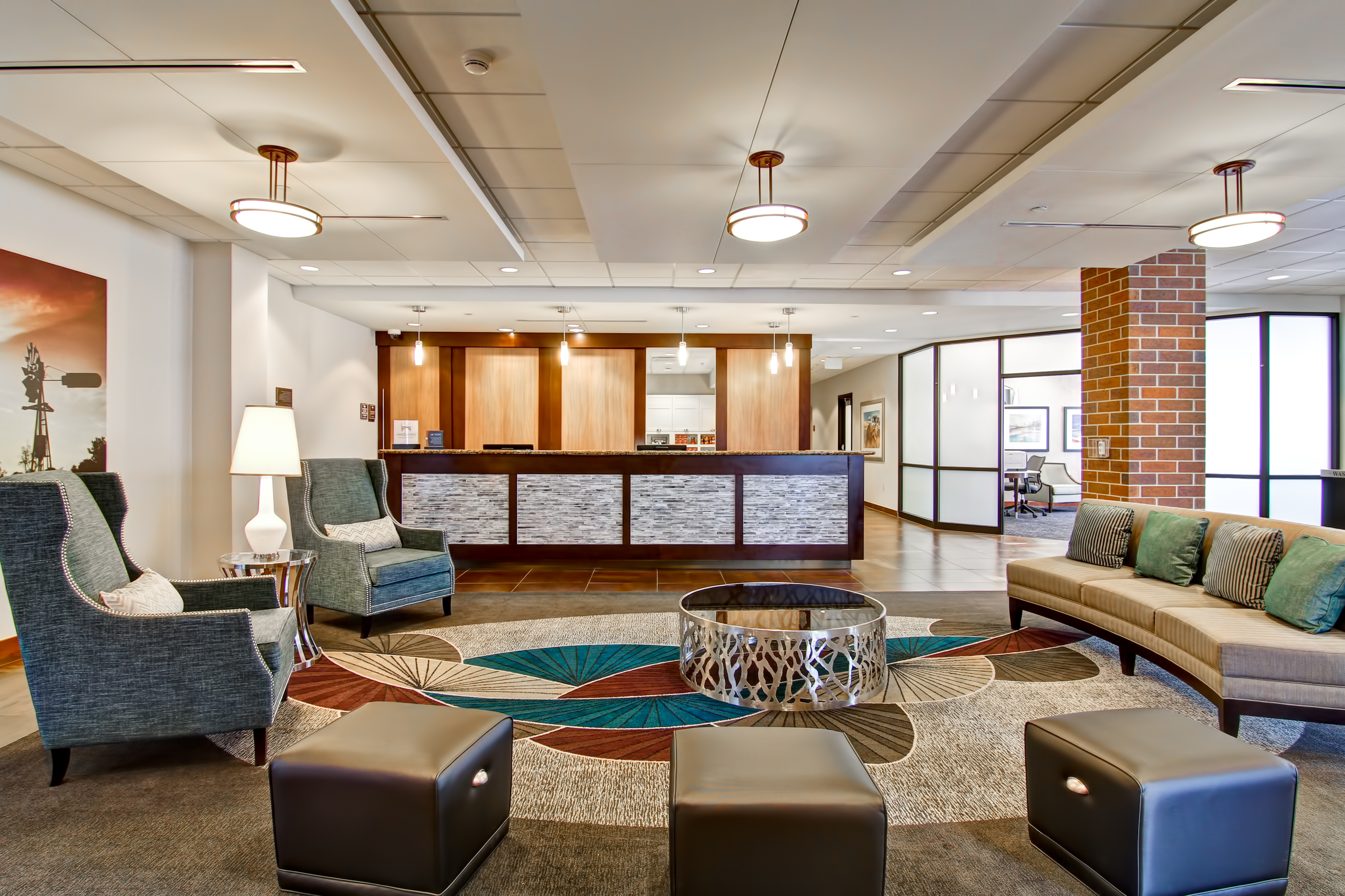Lobby Seating Area With Ottomans, Arm Chairs, Wall Art, Sofa, Table, and Views of Front Desk and Business Center