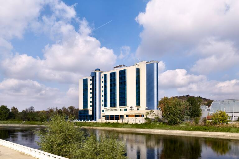 Widok na fasadę hotelu, oznakowanie i krajobraz z rzeki