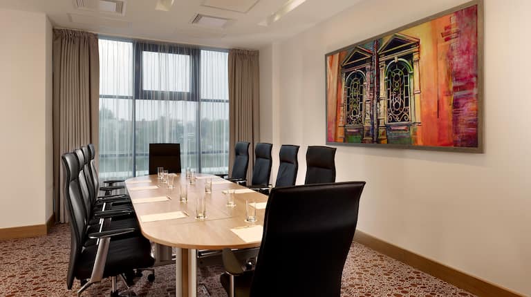 Window With Sheer Drapes, Wall Art, and Seating for 10 at Boardroom Table With Drinking Glasses, and Notepads in Augustia Boardroom