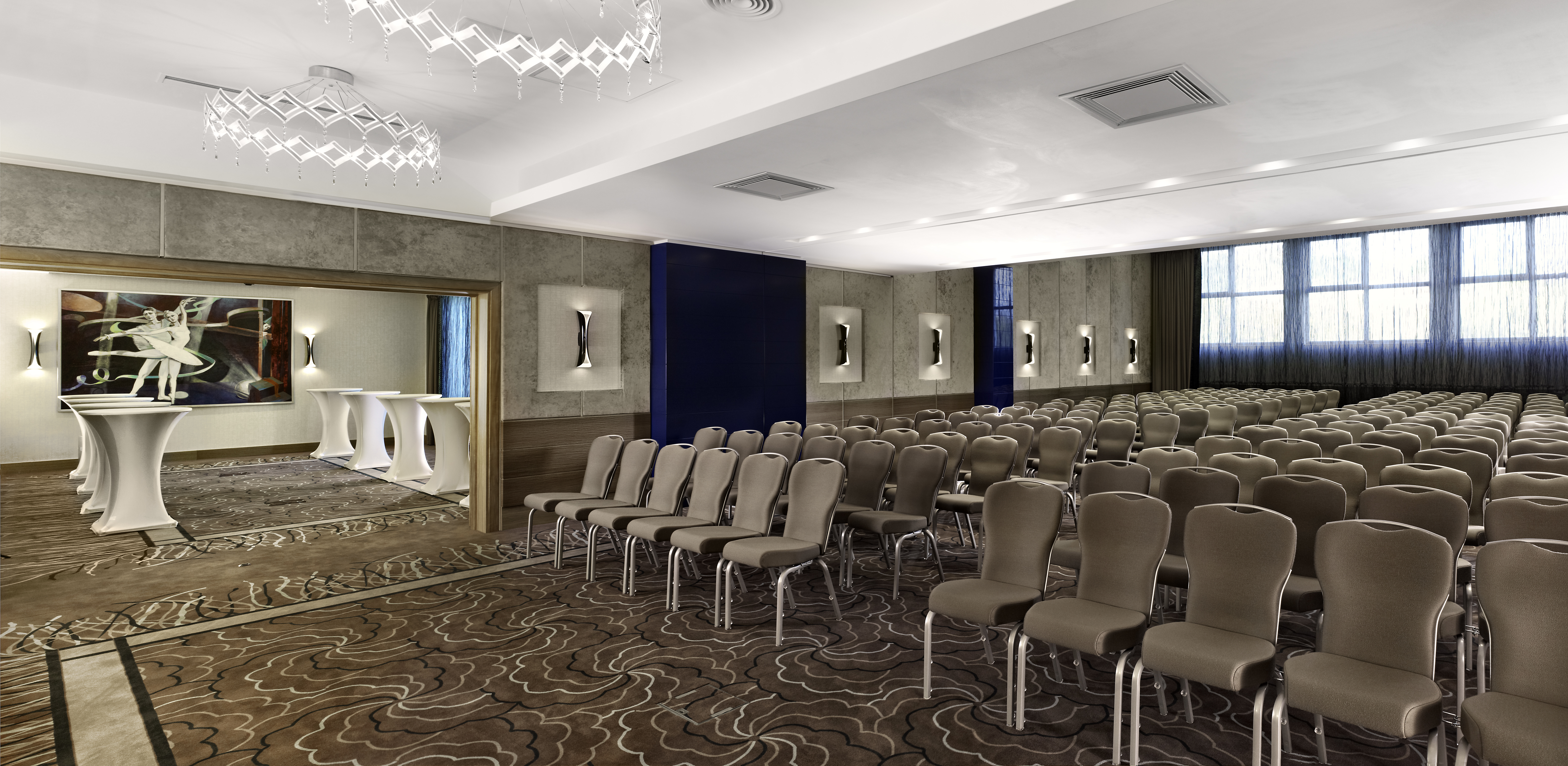 Varadinum Ballroom With Rows of Chairs Arranged Theater Style and View of Cocktail Tables and Wall Art in Breakout Room