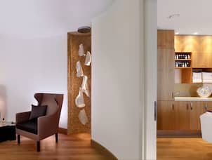 Spa Corridor With Table, FLoor Lamp, Armchair and View Into Massage Room With Table and Fresh Towels