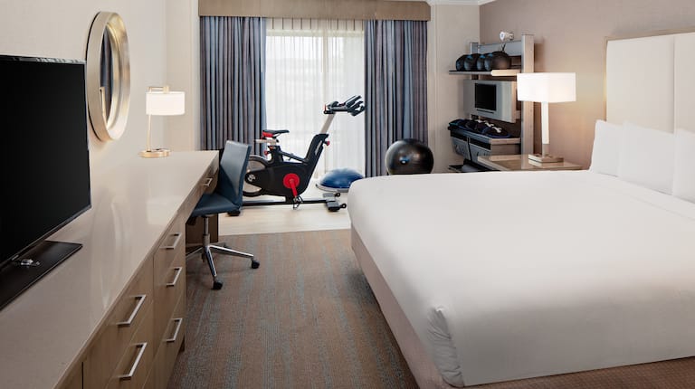 Guest Room with Large Bed Desk HDTV and Exercise Equipment