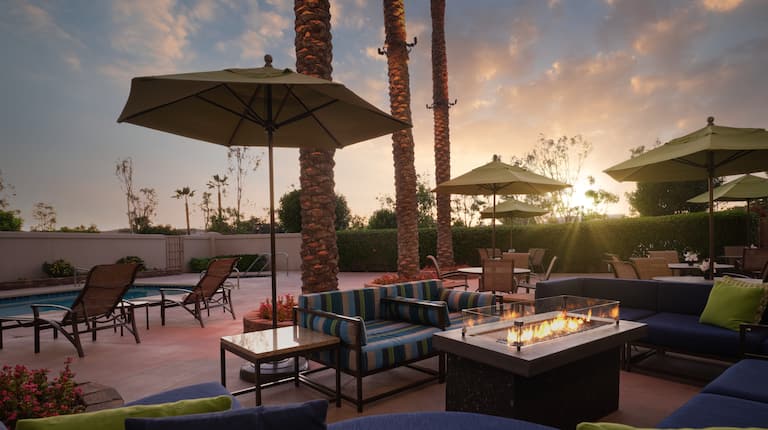 pool and patio area with comfortable seats around a fire pit at sunset