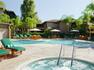 Outdoor Pool and Hot Tub With Green Loungers Tables, Sun Umbrellas, and Chairs