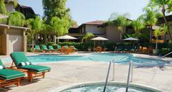 Outdoor Pool and Hot Tub With Green Loungers Tables, Sun Umbrellas, and Chairs