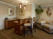 Wetbar Area With Wall Art, Coffee Maker, Counter Seating, Armchair and Ottoman in Suite