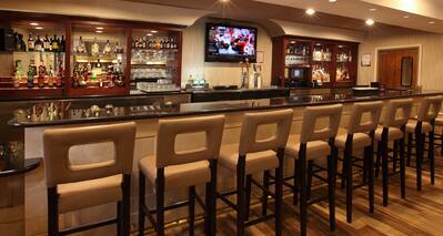 Angled View of Counter Seating and TV at Fully Stocked Bar