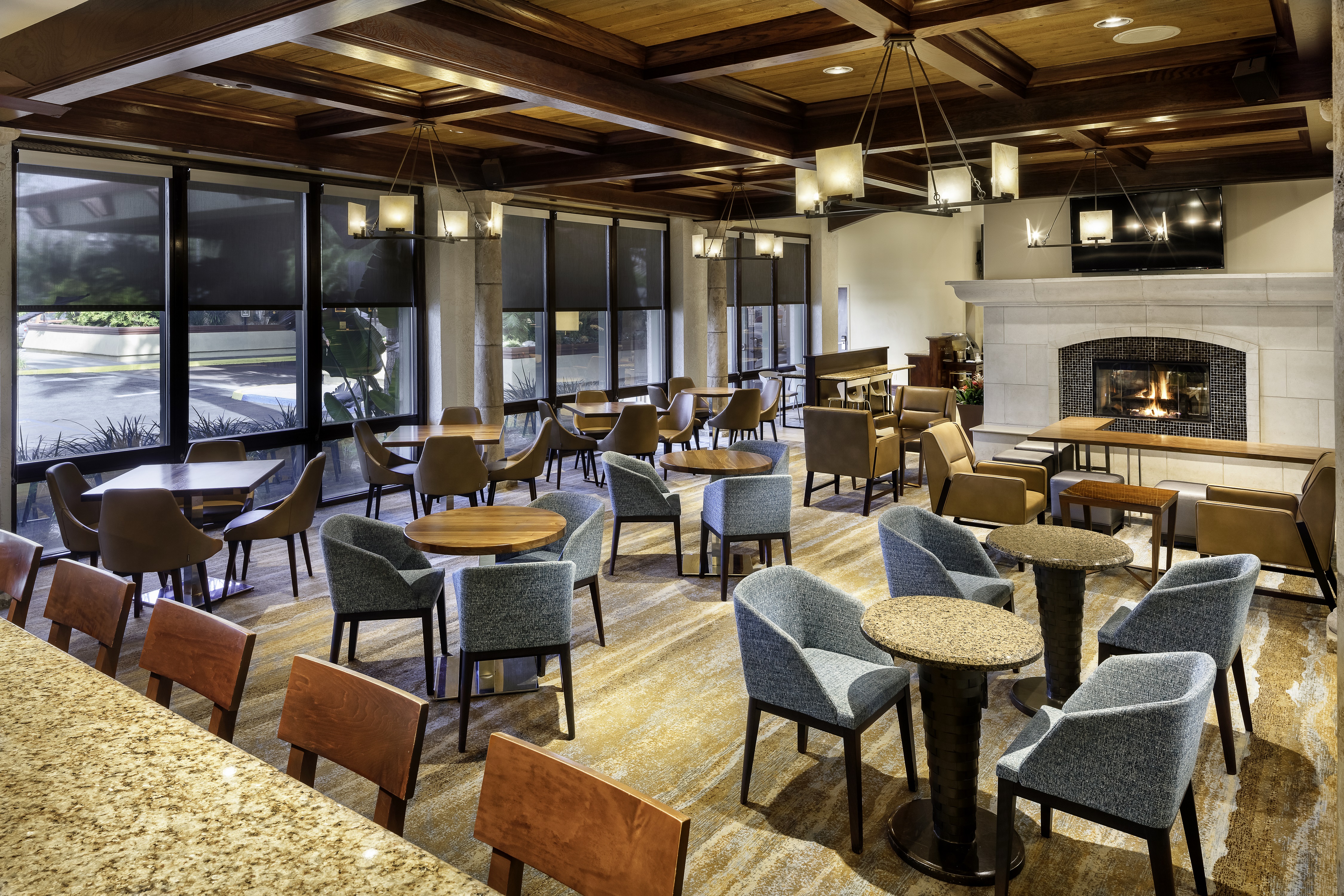 Vineyards Restaurant Dining Room Area With Tables, Mixed Seating, Large Windows, and TV Above Fireplace