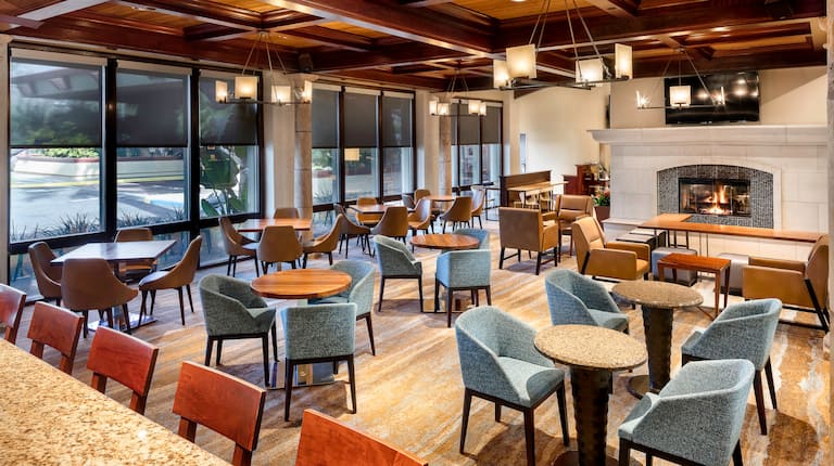 Vineyards Restaurant Dining Room Area With Tables, Mixed Seating, Large Windows, and TV Above Fireplace