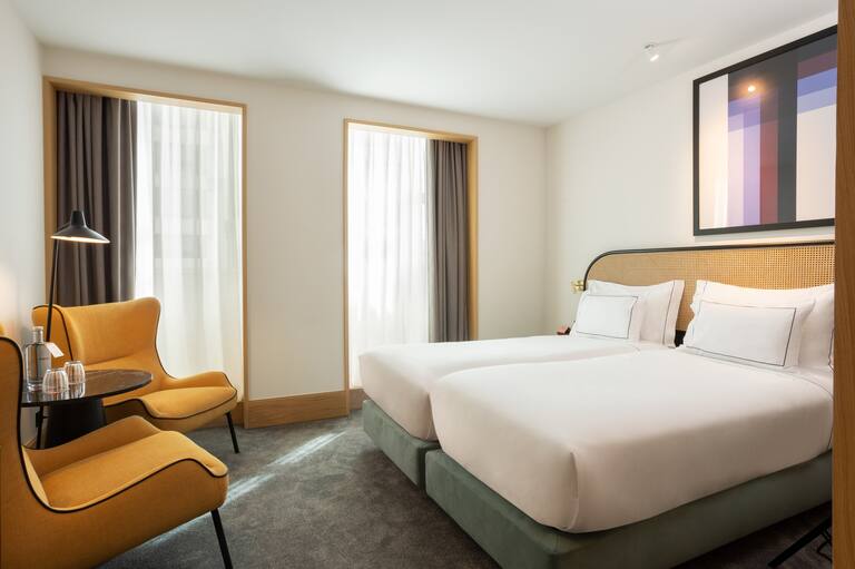 Zwei Betten im Zimmer mit gelbem Stuhl und Lampe