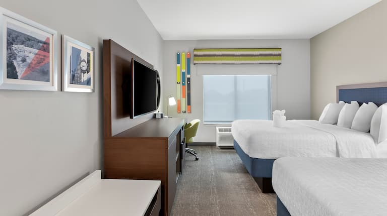 guestroom with double queen beds, work desk, and tv