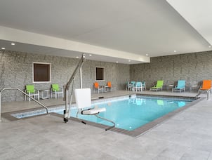 Spacious indoor pool featuring ample seating, complimentary towels, and convenient accessible chair lift.