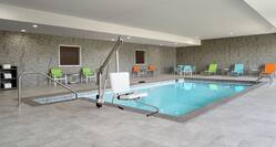 Spacious indoor pool featuring ample seating, complimentary towels, and convenient accessible chair lift.