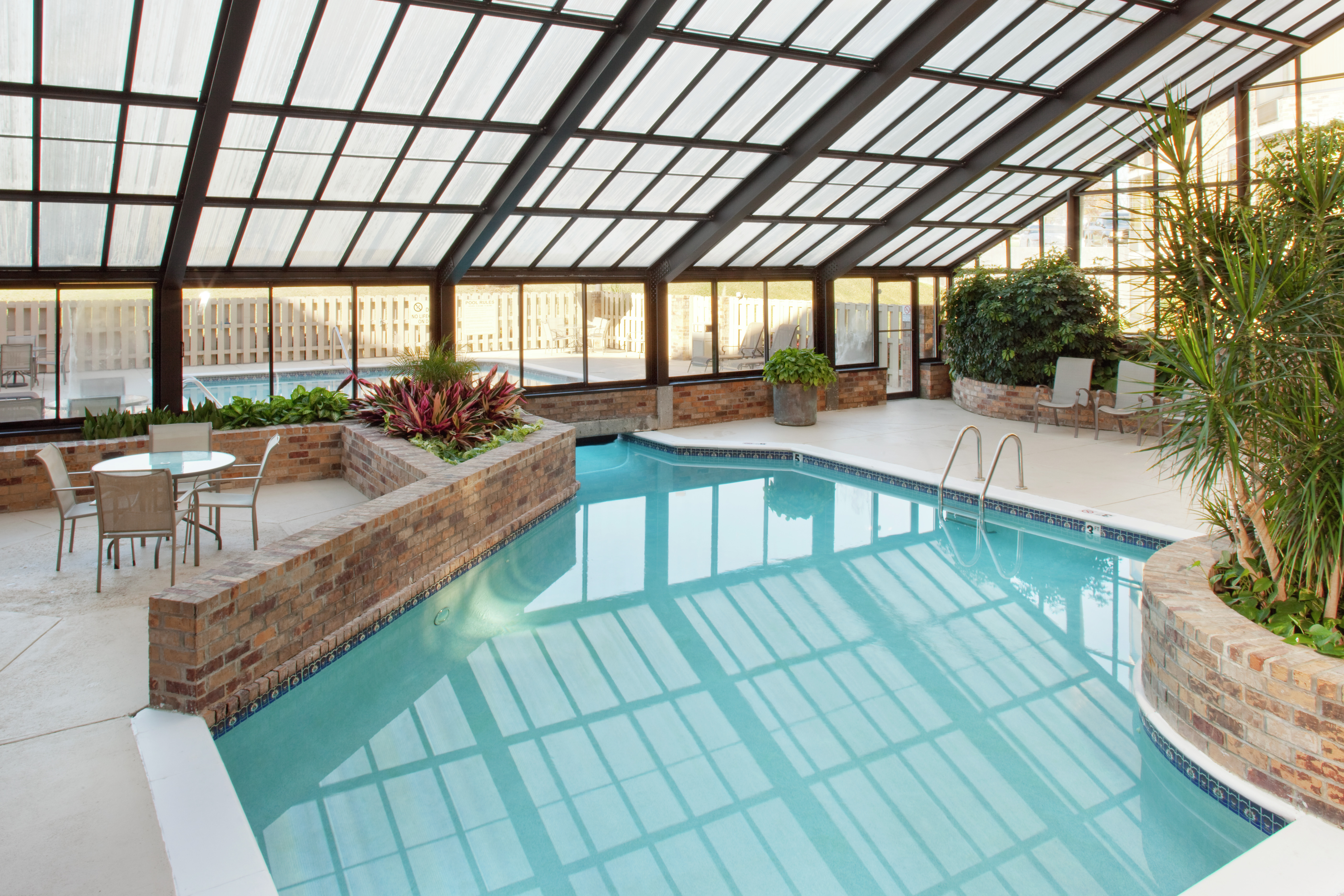 Tables, Chairs and Loungers by Indoor Pool With Windows and Skylight