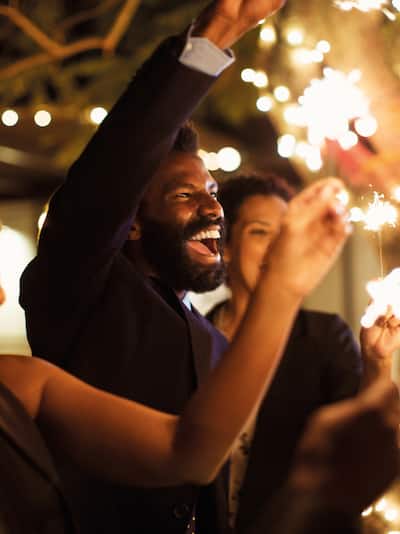 Des personnes souriantes et s'attirant des scintillants lors d'un événement en soirée