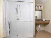 Suite Roll-in Shower with Folded Shower Chair, Grab Bars, and Accessible Sink