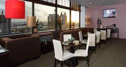 Tables, White Chairs, Lamps, Lounge Seating, TV, and Window With Sunset View in Executive Floor
