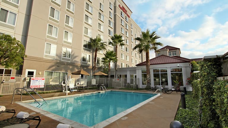 Daytime View of Hotel Exterior With Signage and Pool Area