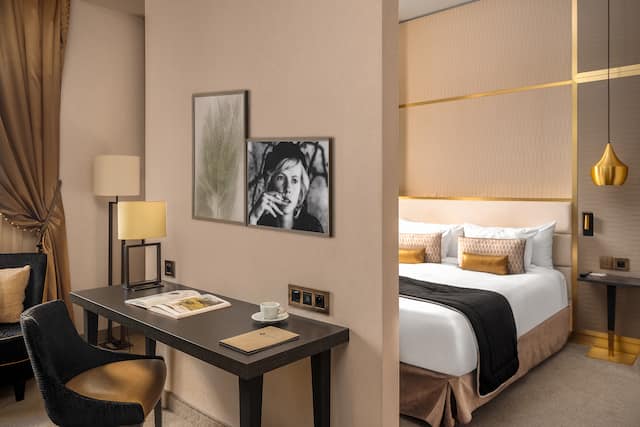 Guest room work desk and TV with opened door to bedroom. with one king bed.