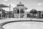 Beautiful outdoor pool featuring covered gazebo and patio tables with umbrellas.
