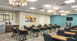Spacious meeting room featuring classroom-style setup with TV, podium, and coffee break station.