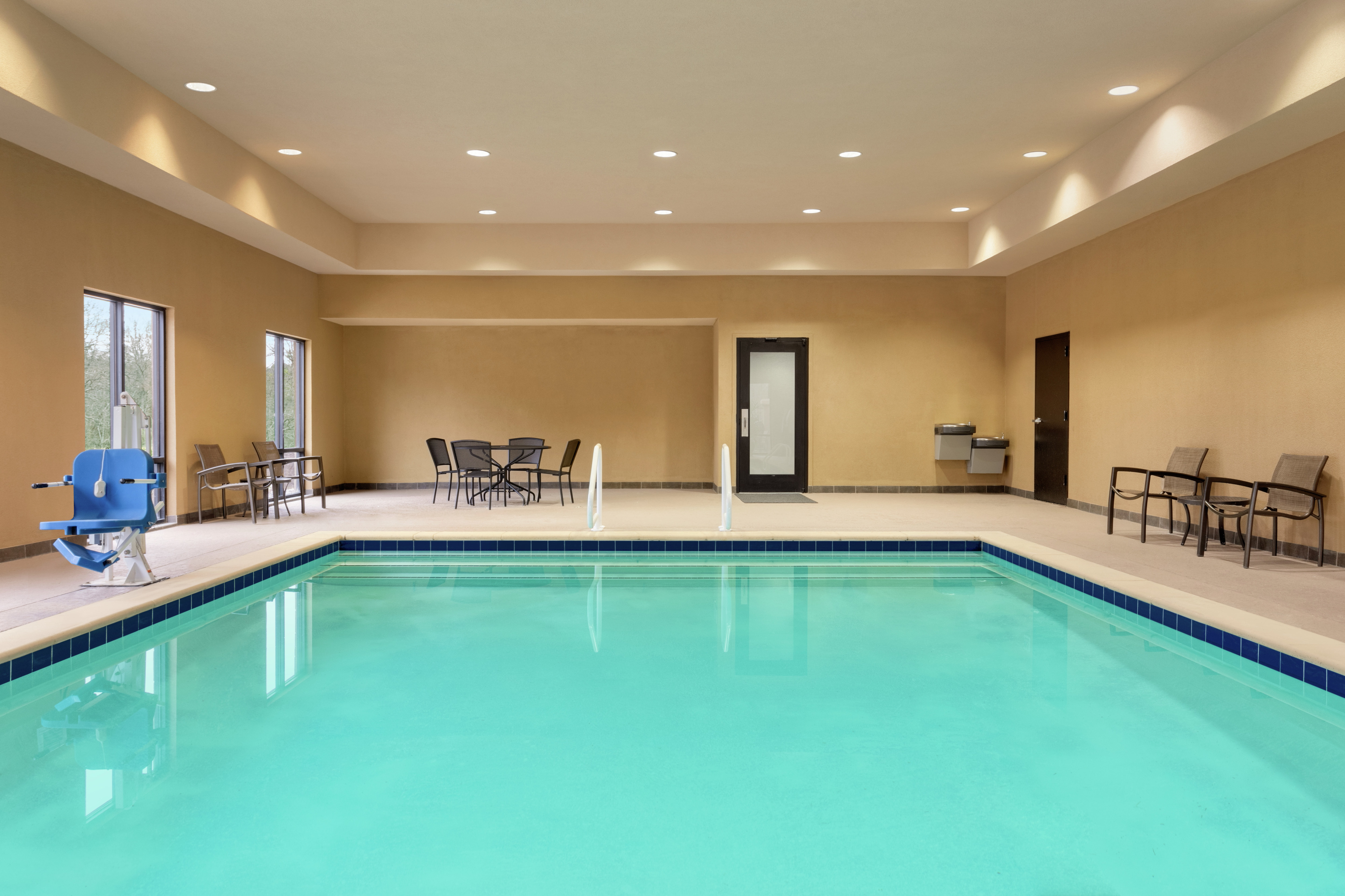 Spacious indoor pool featuring large windows with ample light, seating, and accessible chair-lift.