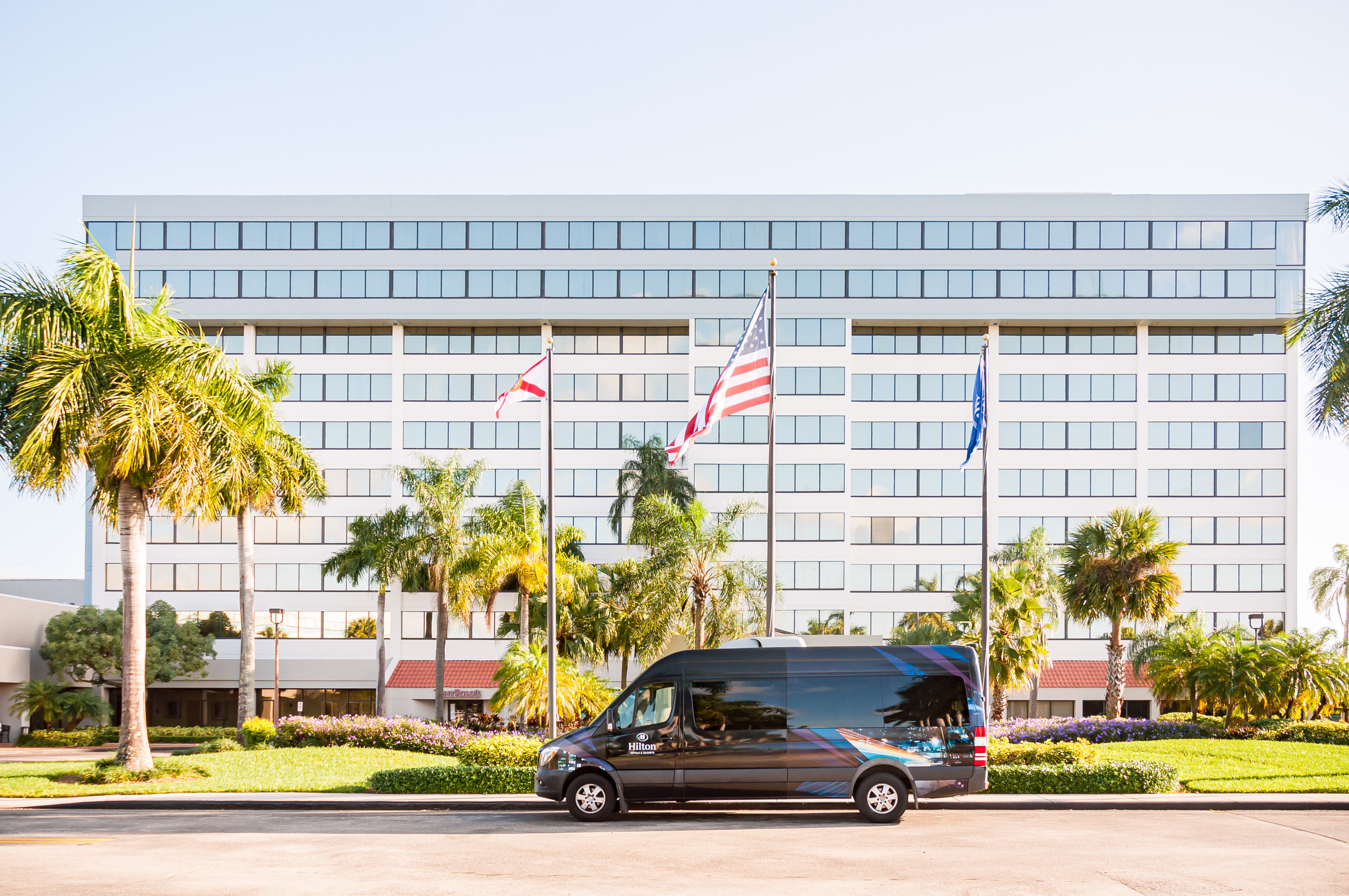 Hotel exterior with shuttle in front and flags