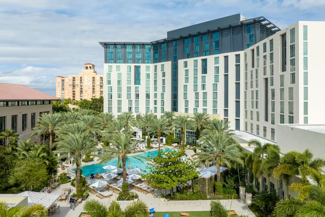 Hilton Hotel Exterior and View of Outdoor Pool with Palm Trees