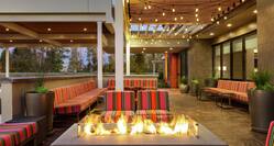 Beautiful outdoor lounge area featuring comfortable sofa style seating, string lights, lush greenery, and firepit.