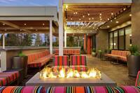 Beautiful outdoor lounge area featuring comfortable sofa style seating, string lights, lush greenery, and firepit.