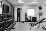 Centru de fitness luminos cu greutăți gratuite, banc de antrenament, mingi de exerciții și televizor.
