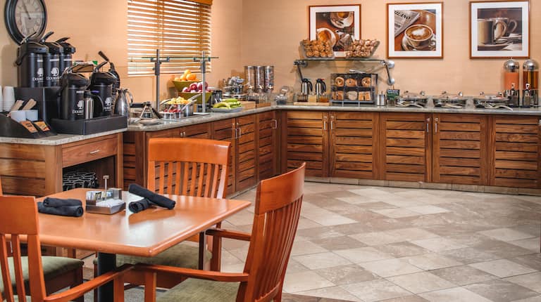 Table, Chairs, Wall Clock, Wall Art, Hot and Cold Buffet Selections on Counters of Breakfast Service Area