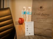 Two Water Bottles, Red Apple, Bag of Amenities, and Signage on Work Desk in King Guestroom