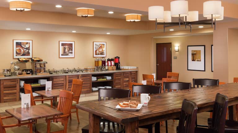 Table, Chairs, Wall Art, Hot and Cold Breakfast Items on Counters of Food Service Area